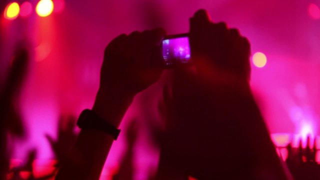 Hands hold camera with digital display among people at party