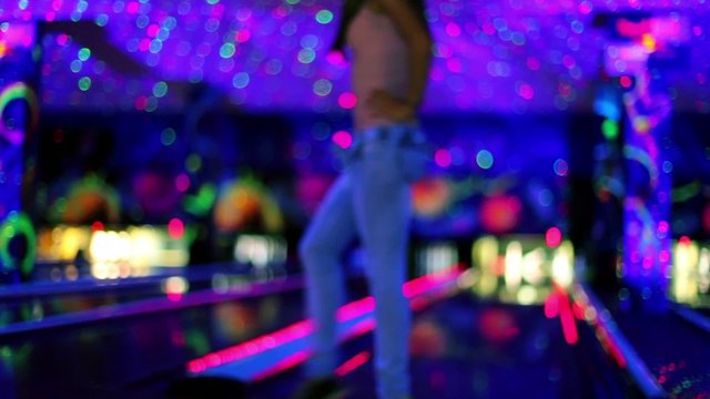 girl throws bowling ball to beat skittles, in club unfocused