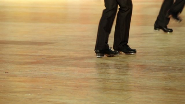 Few boys in shoes with taps and black pants tap dance