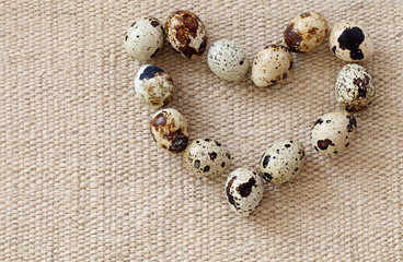 Quail eggs in the shape of heart on a sacking.