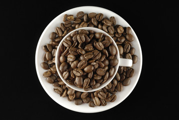 Café en grano y taza sobre fondo negro