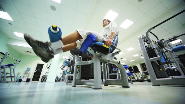 man does exercise for legs while sitting on exerciser in gym