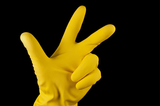 Hand in yellow glove making sign tree fingers