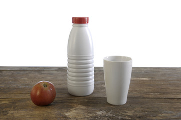 milk bottle, cup and apple on old weathered table