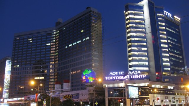 Cars go on street in front of two skyscrapers