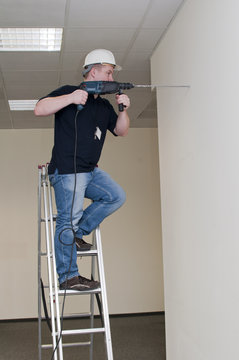 man on a ladder drills drill