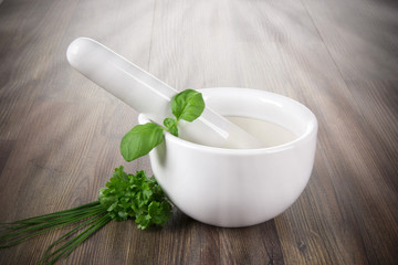 mortar with fresh herbs on wood background