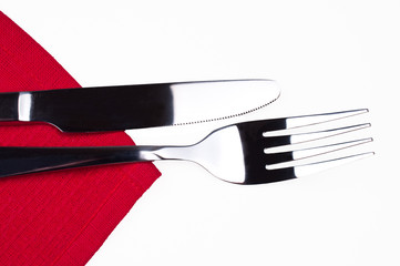 Knife and fork on red tablecloth isolated