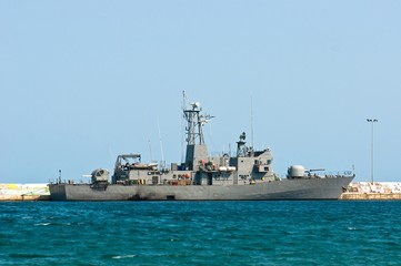 Big battle ship in the dock against blue sky and mountains