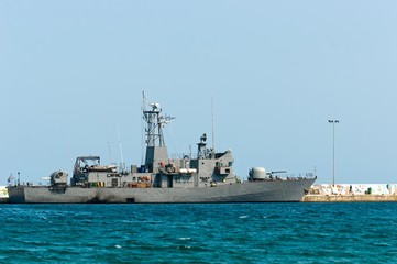Big battle ship in the dock against blue sky and mountains