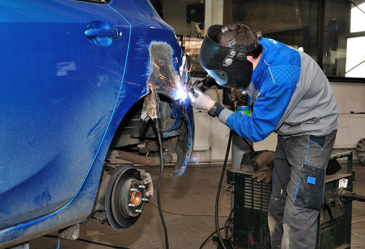 Worker welding a car body.