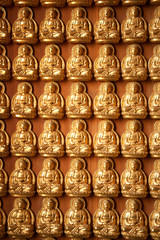 Little golden buddha on the wall background .