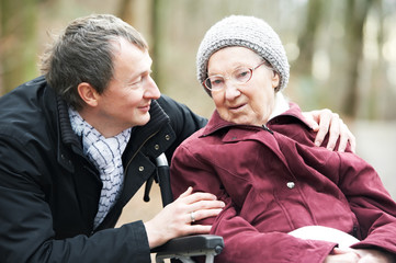 old senior woman in wheelchair with careful son