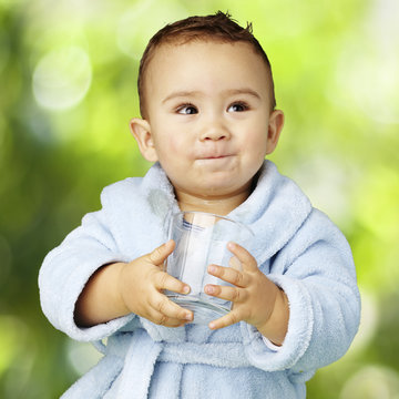 portrait of adorable infant with blue bathrobe holding a glass a