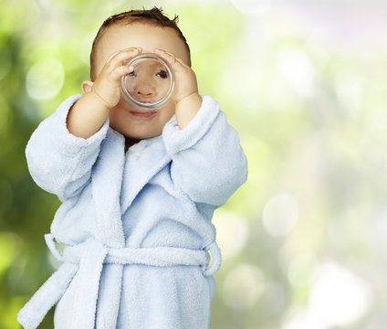 portrait of adorable infant with blue bathrobe drinking water at
