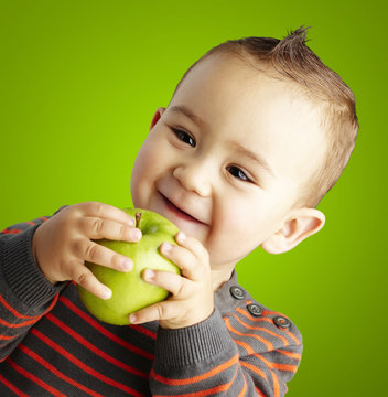 portrait of funny kid holding green apple and smiling over green