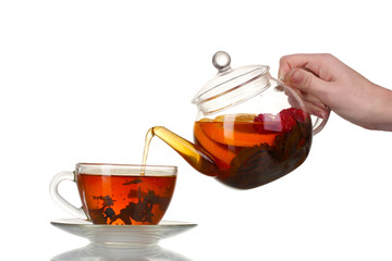 Glass teapot pouring black tea into cup isolated on white