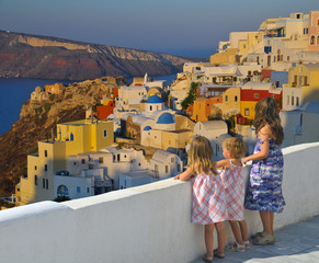 Little girls watching the sunset over Oia village - Greece - obrazy, fototapety, plakaty