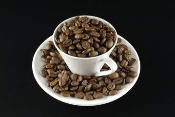 Café en grano y taza sobre fondo nego