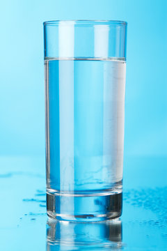 Glass of water on blue background