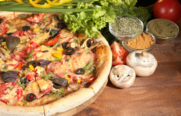 delicious pizza, vegetables and spices on wooden table