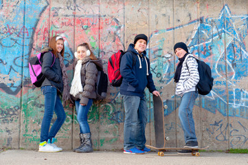Obraz na płótnie Canvas Happy teenage friends with school bags and skateboards