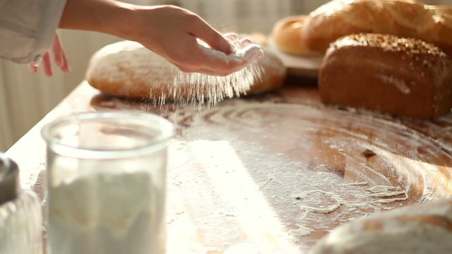 Baker hand throwing flour on the table, slow motion