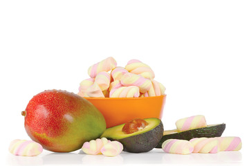 Sliced fresh avocado, mango and candies on a white background
