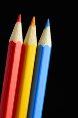 Red, Yellow and Blue Pencils on Black Background