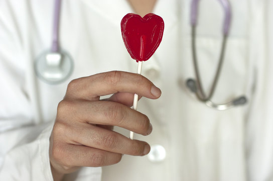 Doctora con una piruleta con forma de coraz&oacute;n en la mano