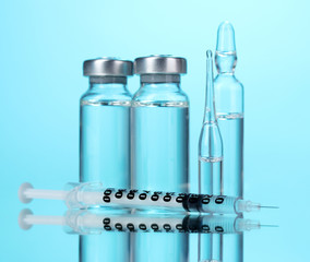 medical ampoules and syringe on blue background