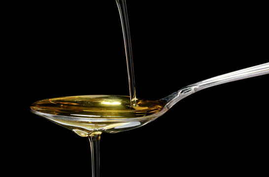 olive oil in spoon on black background