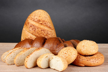 rye and white bread and buns on wooden table on gray background