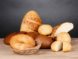 rye and white bread and buns on wooden table on gray background