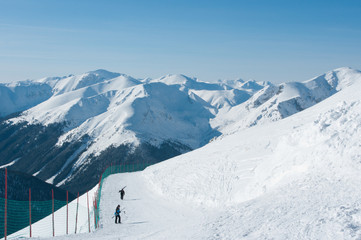 Fototapeta na wymiar Panorama Tatr w zimie i narciarze wchodzący na Kasprowy Wierch