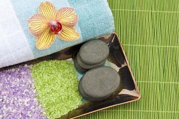 Spa concept with mineral bath salt, massage stones, towel and or