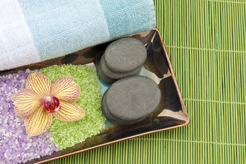Spa concept with mineral bath salt, massage stones, towel and or