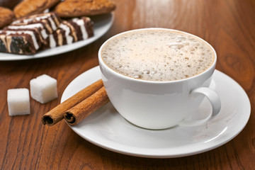 Cappuccino with cinnamon bark, lump sugar and sweets