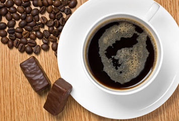 Cup of coffee, coffee beans and chocolate candies, top view