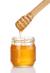 Jar of honey and wooden drizzler isolated on white