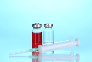 Syringe and medical ampoules on blue background