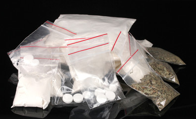 Cocaine and marihuana in packages on black background