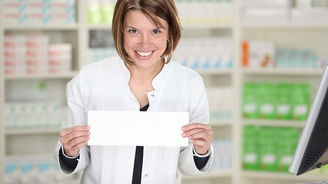 l&auml;chelnde apothekerin zeigt wei&szlig;es schild