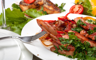 A fork with sausages and grilled vegetables