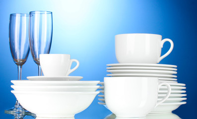 empty bowls, plates, cups and glasses on blue background