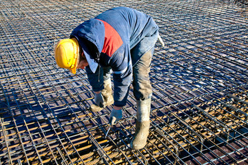 Man worker installing binding wires to reinforcement steel bars