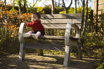 baby sitting on a park bench