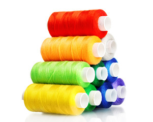 Pyramid of many-coloured bobbins of thread isolated on white