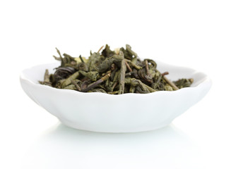 Green dry tea leaves in plate isolated on white