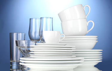 empty bowls, plates, cups and glasses on blue background